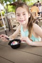 Cute smiling little girl eating a delicious bowl of ice cream at an outdoor cafe