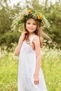 Cute smiling little girl  with flower wreath on the meadow at the farm. Portrait of adorable small kid outdoor Royalty Free Stock Photo
