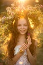 Cute smiling little girl with flower wreath on the meadow at the farm. Portrait of adorable small kid outdoor