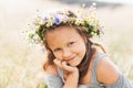 Cute smiling little girl with flower wreath on the meadow. Portrait of adorable small kid outdoors Royalty Free Stock Photo