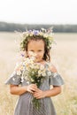 Cute smiling little girl with flower wreath on the meadow. Portrait of adorable small kid outdoors Royalty Free Stock Photo