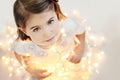 Cute, smiling little girl with glowing Christmas lights Royalty Free Stock Photo