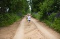 A cute smiling little girl running barefoot in a countryside landscape along a country path Royalty Free Stock Photo