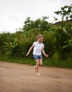 A cute smiling little girl running barefoot in a countryside landscape along a country path Royalty Free Stock Photo