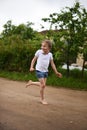 A cute smiling little girl running barefoot in a countryside landscape along a country path Royalty Free Stock Photo