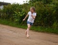 A cute smiling little girl running barefoot in a countryside landscape along a country path Royalty Free Stock Photo