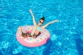 Cute smiling little girl in swimming pool with rubber ring. Child having fun on vacation