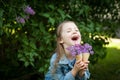 Little girl with waffle ice cream cone filled with lilac flowers in her hands Royalty Free Stock Photo