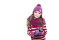 Cute smiling little girl wearing purple knitted scarf, hat and gloves, holding christmas gift isolated on white background. Royalty Free Stock Photo