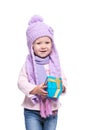 Cute smiling little girl wearing violet knitted scarf and hat, holding christmas gift isolated on white background. Winter clothes Royalty Free Stock Photo