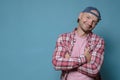 Cute, smiling man stands with crossed arms. Copy space. Blue background.