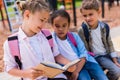 Multiethnic schoolkids reading book Royalty Free Stock Photo