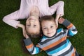 Cute smiling older sister 7 years old and younger brother 3 years old lie side by side on the grass, look up Royalty Free Stock Photo