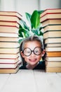 Cute smiling portrait of preschool age girl in round shaped glasses between books pile with copy space