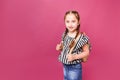 Cute smiling schoolgirl in uniform standing on pink background with copy space