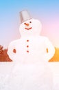 Cute smiling snowman in the field covered with snow. Artistically colored photography