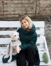 Cute smiling teenage girl walks with her pet, young white dog in cold season Royalty Free Stock Photo