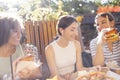 Cute smiling teenage girls are sitting in open air cafe and eating fast food Royalty Free Stock Photo