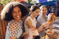 Cute smiling teenage girls are sitting in open air cafe and eating fast food Royalty Free Stock Photo