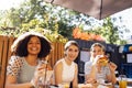 Cute smiling teenage girls are sitting in open air cafe and eating fast food Royalty Free Stock Photo