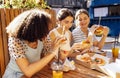 Cute smiling teenage girls are sitting in open air cafe and eating fast food Royalty Free Stock Photo