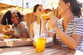 Cute smiling teenage girls are sitting in open air cafe and eating fast food Royalty Free Stock Photo