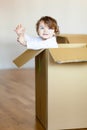 Toddler baby girl sitting inside brown cardboard box. Royalty Free Stock Photo