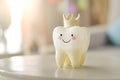 Cute smiling tooth with crown as children toy on table