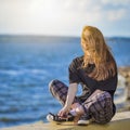 Cute Smiling Winsome Relaxing Caucasian Blond Female Girl Posing Outdoors While Sitting Outdoors At Sunny Day Near Seashore