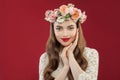 Cute smiling woman in summer rose wreath portrait. Cheerful model with flowers on red wall background Royalty Free Stock Photo