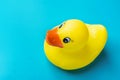 Cute smiling yellow wet rubber bath duck with water drops on blue background. Toddler munchkin toys. Kids hygiene swimming fun