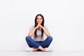 Cute smiling young girl is sitting on the floor with crossed leg