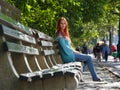 Cute smiling young woman in blue jacket sitting at bench, central park, New-York Royalty Free Stock Photo