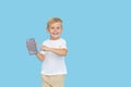 Cute smilling child boy with smartphone on blue background. Advertising of educational applications on a mobile