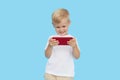 Cute smilling child boy with smartphone on blue background. Advertising of educational applications on a mobile