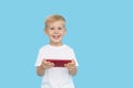 Cute smilling child boy with smartphone on blue background. Advertising of educational applications on a mobile