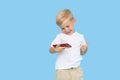 Cute smilling child boy with smartphone on blue background. Advertising of educational applications on a mobile phone