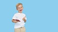 Cute smilling child boy with smartphone on blue background. Advertising of educational applications on a mobile phone