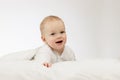 Cute smilling 9 month boy in white bodysuite on white background. Laughing infant kid under blanket. Copy space. Royalty Free Stock Photo
