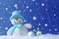 Cute snowman and Christmas balls on snow against blue background, bokeh effect. Space for text Royalty Free Stock Photo