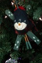 Cute snowman ornament in a green cap and muffler with skis and poles crossed behind.