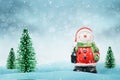 Cute snowman in Santa Claus clothes. Christmas trees beside