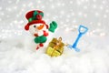 Cute snowman in snow with shovel and gift Royalty Free Stock Photo