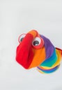 Cute sock puppet with rainbow flag sock, and plastic red eyes. White background, copy space. Fighting for LGBTQ+ rights
