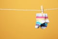 Cute socks for baby on laundry line against color background. Royalty Free Stock Photo