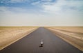 Cute soft toy sitting in middle of empty desert road with diminishing perspective, Mauritania, Africa