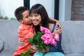 Cute son hugging his mother after giving her flowers Royalty Free Stock Photo