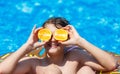 Cute sporty boy swims in the pool with donut ring and has fun, smiles, holds oranges. vacation with kids, holidays, active weekend Royalty Free Stock Photo