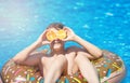 Cute sporty boy swims in the pool with donut ring and has fun, smiles, holds oranges. vacation with kids, holidays, active weekend Royalty Free Stock Photo