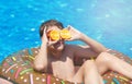 Cute sporty boy swims in the pool with donut ring and has fun, smiles, holds oranges. vacation with kids, holidays, active weekend
